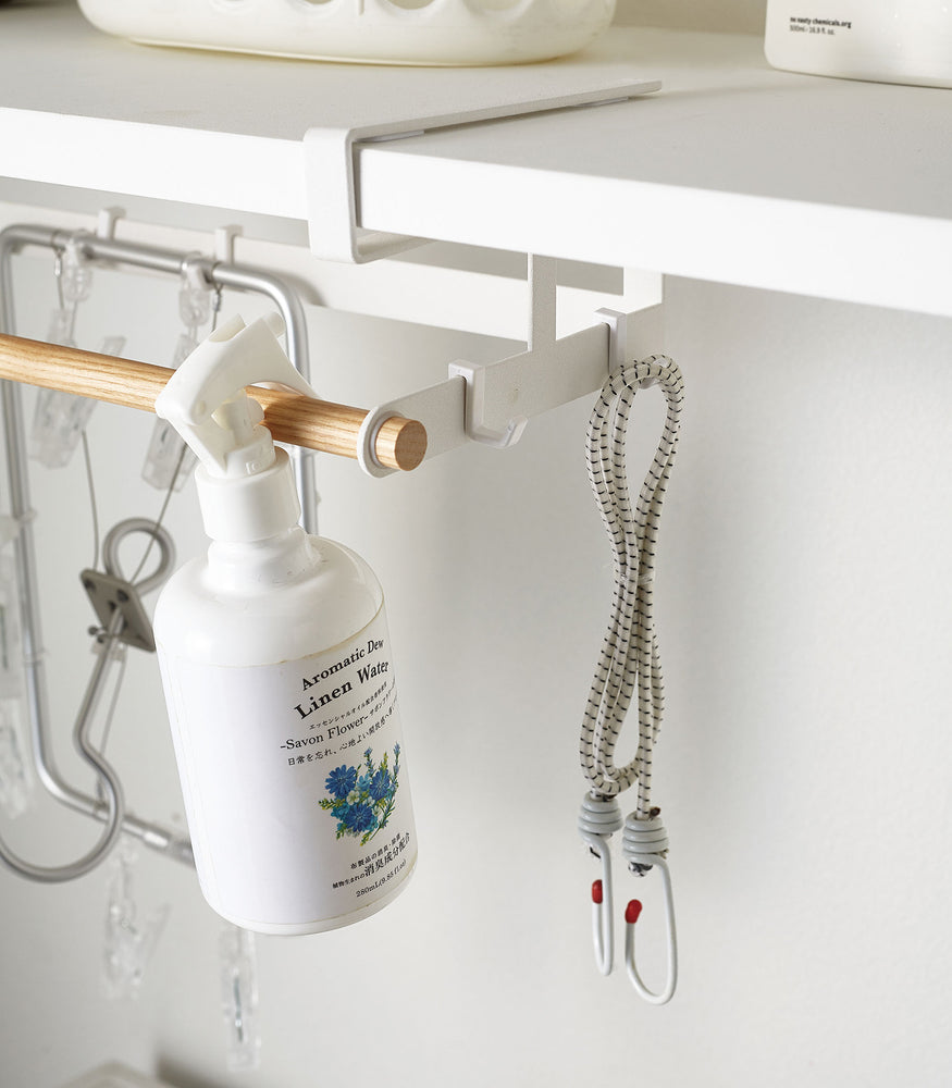 View 6 - Close up of white Undershelf Hanger holding cleaning supplies by Yamazaki Home.