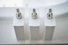 Aerial view of Yamazaki Home white Shampoo, Conditioner, and Body Soap dispensers. view 5