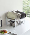 White Expandable Countertop Organizer holding bottles on kitchen countertop by Yamazaki Home.