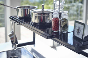 Close up view of black Expandable Kitchen Support Rack holding pots and ingredients in kitchen by Yamazaki Home. view 17