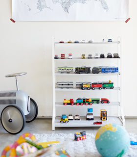 Front view of white Kids' Parking Garage displaying toy trains and cars in playroom by Yamazaki Home. view 6
