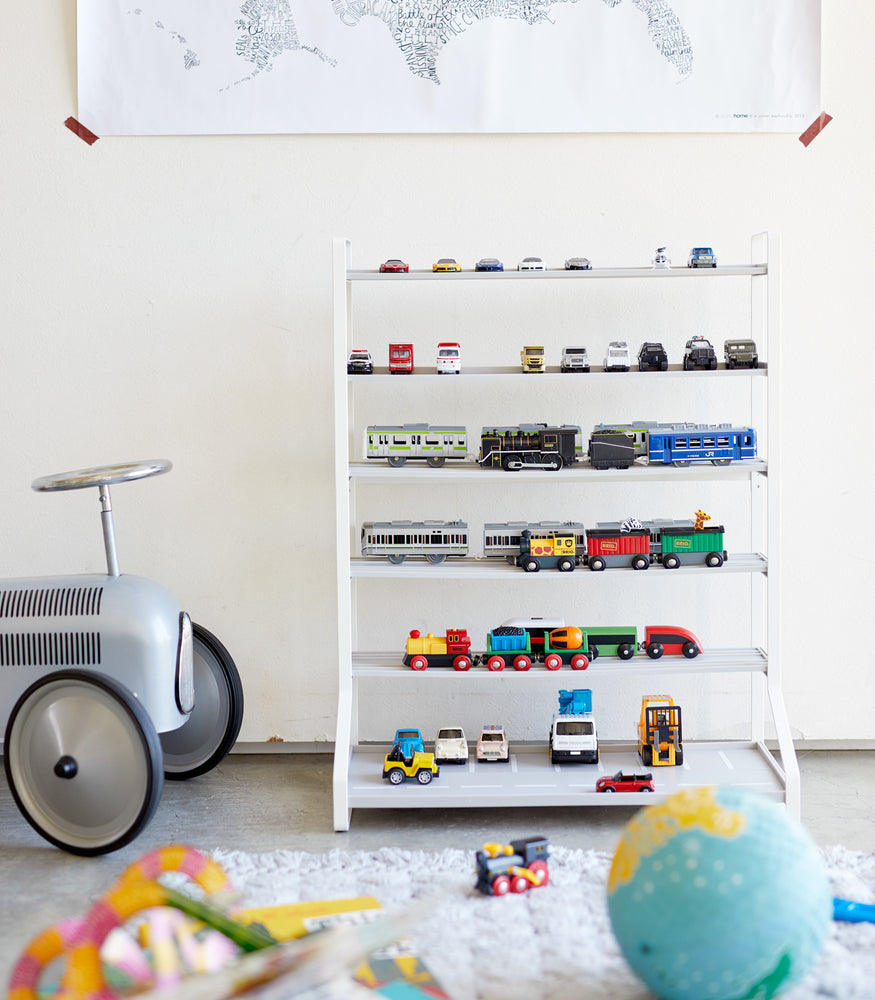 View 6 - Front view of white Kids' Parking Garage displaying toy trains and cars in playroom by Yamazaki Home.