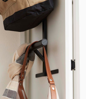 Close up side view of Black Kids' Backpack Hanger holding backpack, scarf, and bag on door by Yamazaki Home. view 11