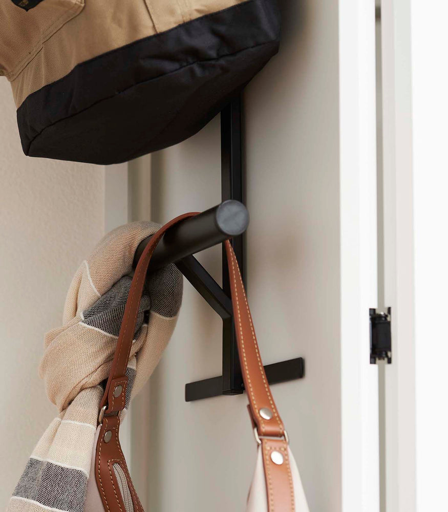 View 11 - Close up side view of Black Kids' Backpack Hanger holding backpack, scarf, and bag on door by Yamazaki Home.