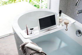 White Expandable Bathtub Caddy holding beauty items and tablet by Yamazaki Home. view 5