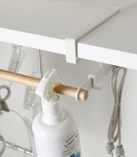 Close up of white Undershelf Hanger holding laundry supplies by Yamazaki Home. view 5
