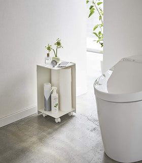 White Rolling Bathroom Organizer holding toilet paper and supplies in bathroom by Yamazaki Home. view 4