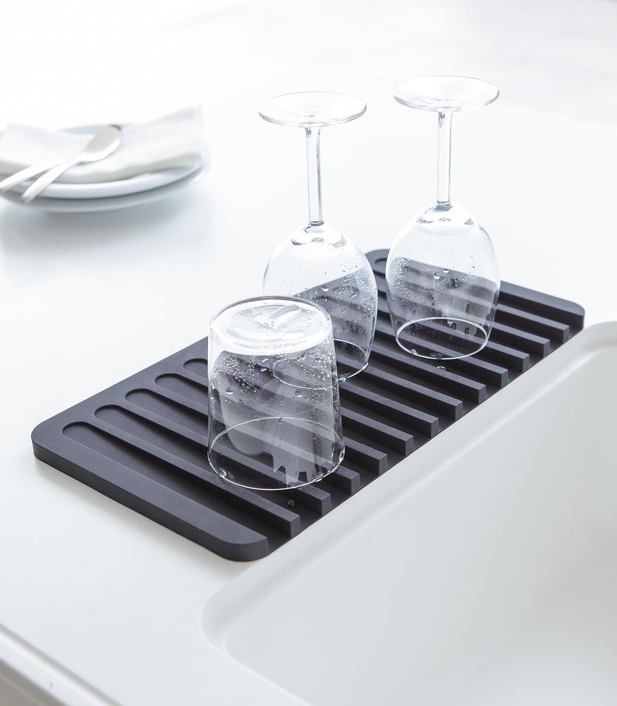 View 4 - Black Dish Drainer Tray containing dinnerware on sink counter by Yamazaki Home.