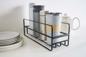 Close up of Yamazaki Home black Glass and Mug Cabinet Organizer next to plates on a shelf view 12