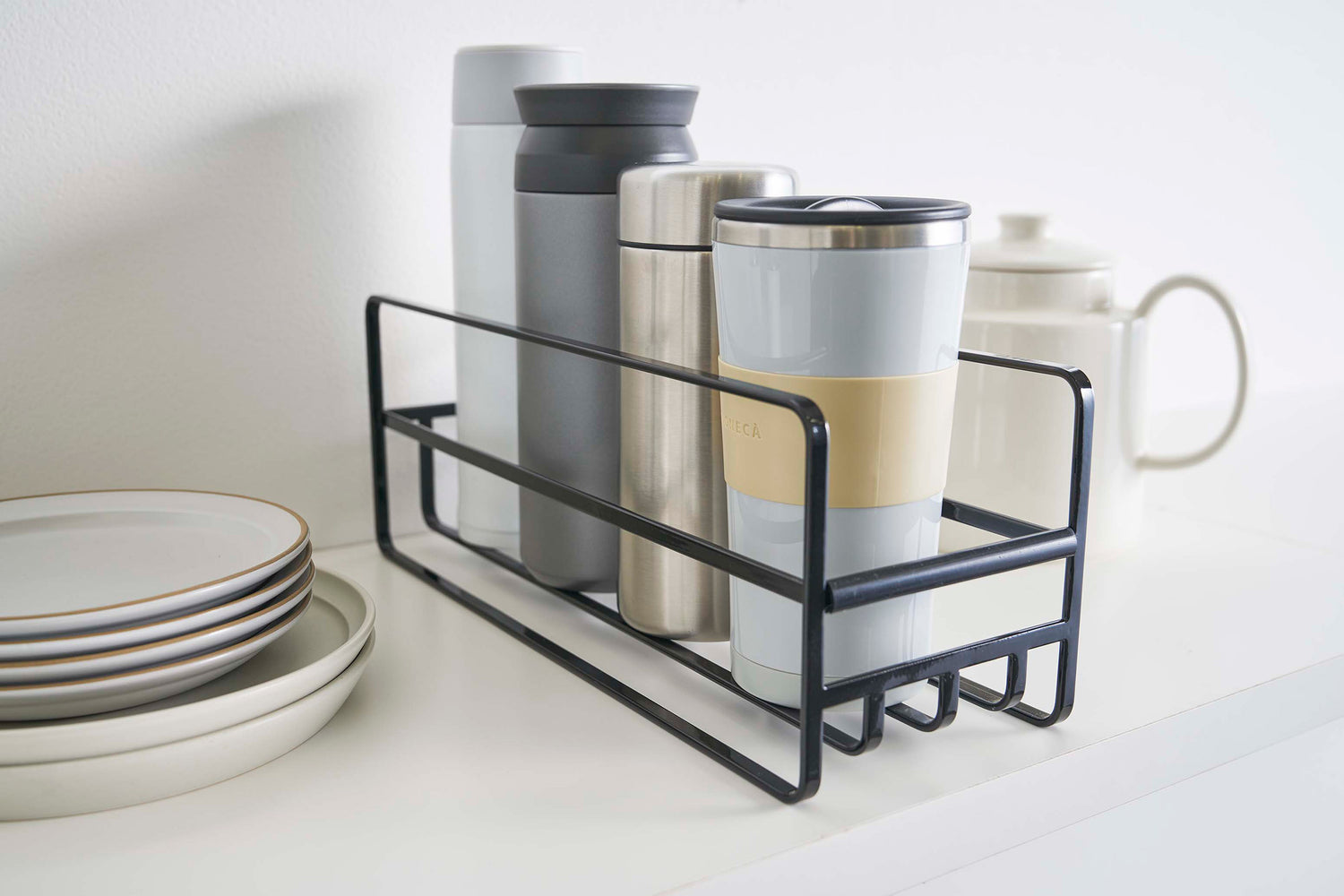 View 12 - Close up of Yamazaki Home black Glass and Mug Cabinet Organizer next to plates on a shelf