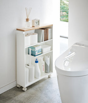 Front view of white Rolling Storage Cart holding bathroom items in bathroom by Yamazaki Home. view 2
