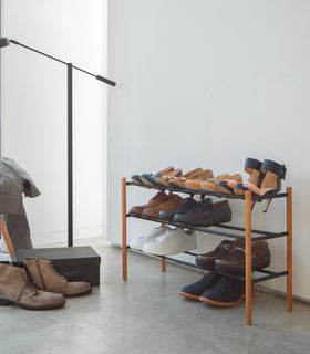 Black Expandable Shoe Rack holding shoes in bedroom by Yamazaki Home. view 9
