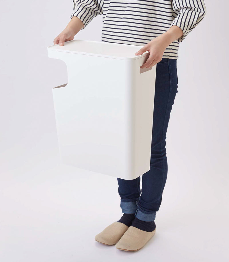 Side view of white Side Table Trash Can being held by model on white background by Yamazaki Home.