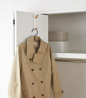 White Over-the-Door Hook on closet door holding jacket by Yamazaki Home. view 4