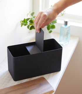 Person inserting divider into black Countertop Organizer with lid off by Yamazaki Home. view 11