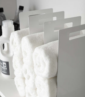 Close up side view of white Towel Storage Organizer holding towels by Yamazaki Home. view 5