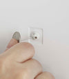 Close up view of person attatching item to white Wall-Mount Storage by Yamazaki Home.