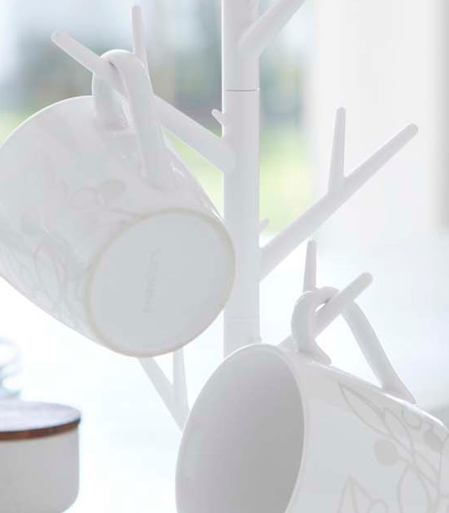 View 5 - Close up view of white Glass & Mug Tree displaying mugs by Yamazaki Home.