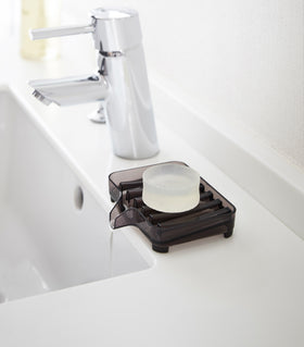 Black Self-Draining Soap Tray holding soap and draining water on sink counter by Yamazaki Home. view 6