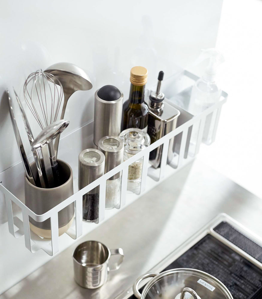 View 3 - Aerial view of white Magnetic Storage Basket holding oils, spices, and utensils in kitchen by Yamazaki Home.