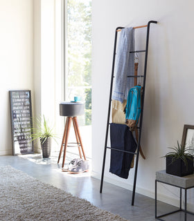 Black Leaning Ladder Rack holding clothing items and accessories in bedroom by Yamazaki Home. view 6