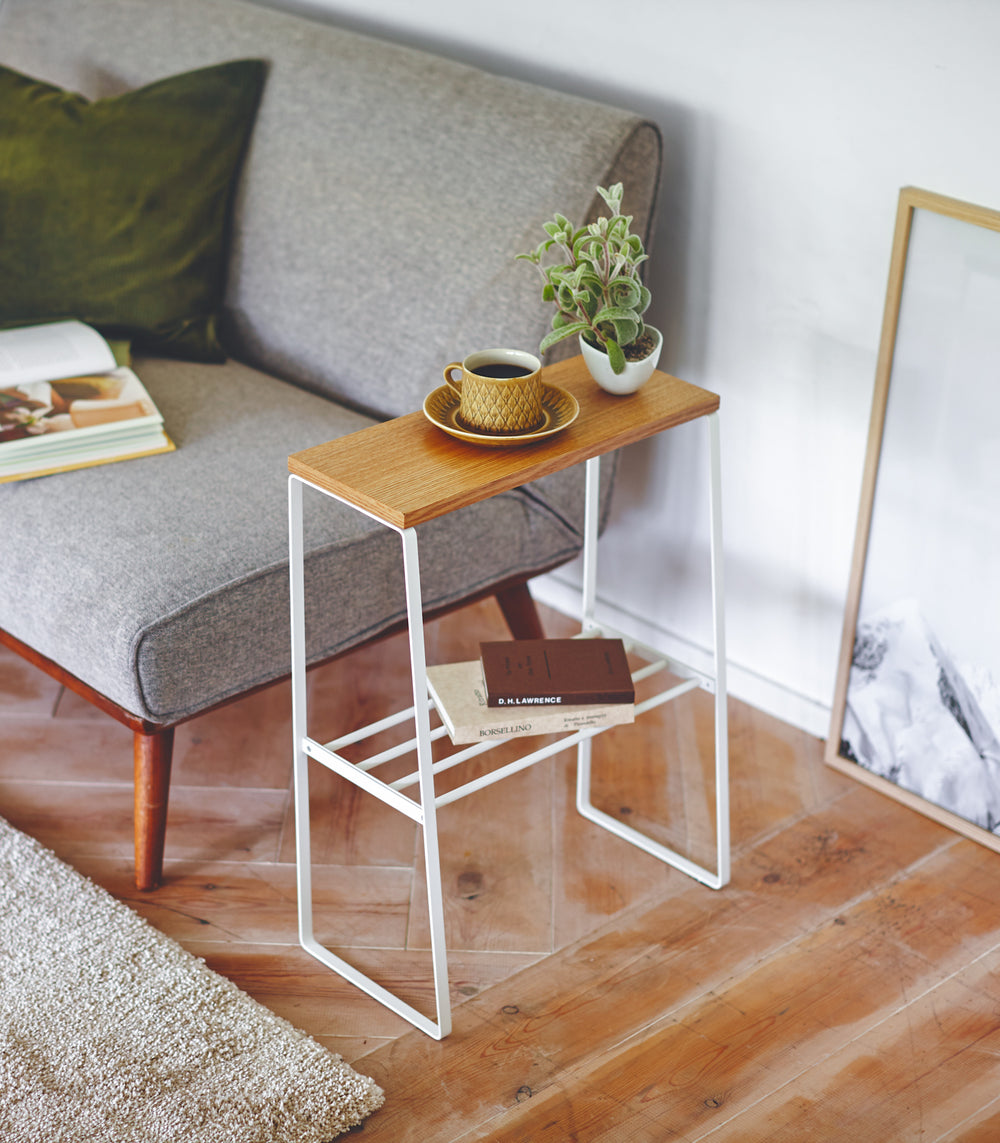 White End Table holding books, cup, and plant in living room by Yamazaki Home.