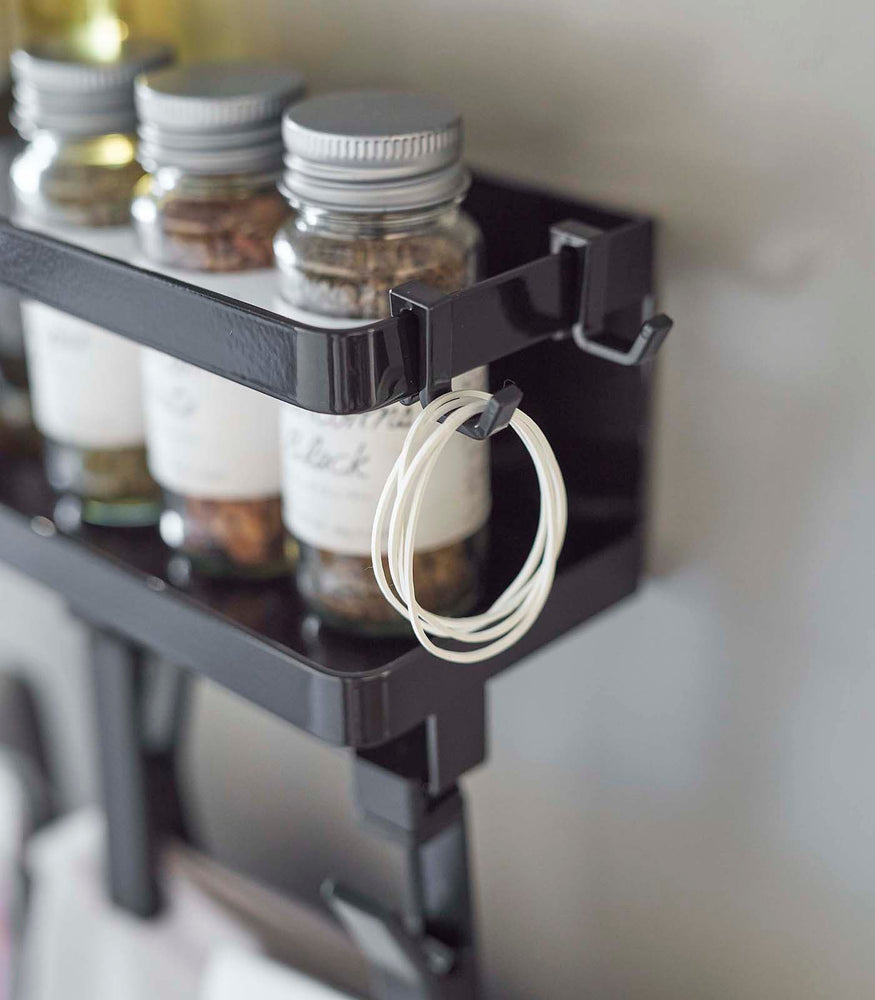 View 11 - Close up view of black Magnetic Organizer with Easy-Grip Rotating Clips hooks holding rubber bands by Yamazaki Home.