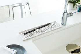 White Sink Drainer Tray holding silverware on sink countertop by Yamazaki Home. view 4