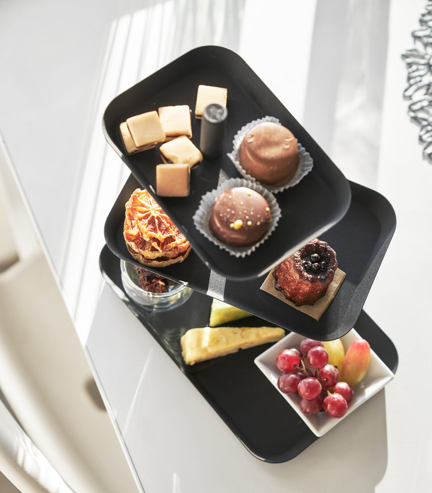 View 9 - Aerial view of black Serving Stand displaying desserts and fruit on white tabletop by Yamazaki Home.