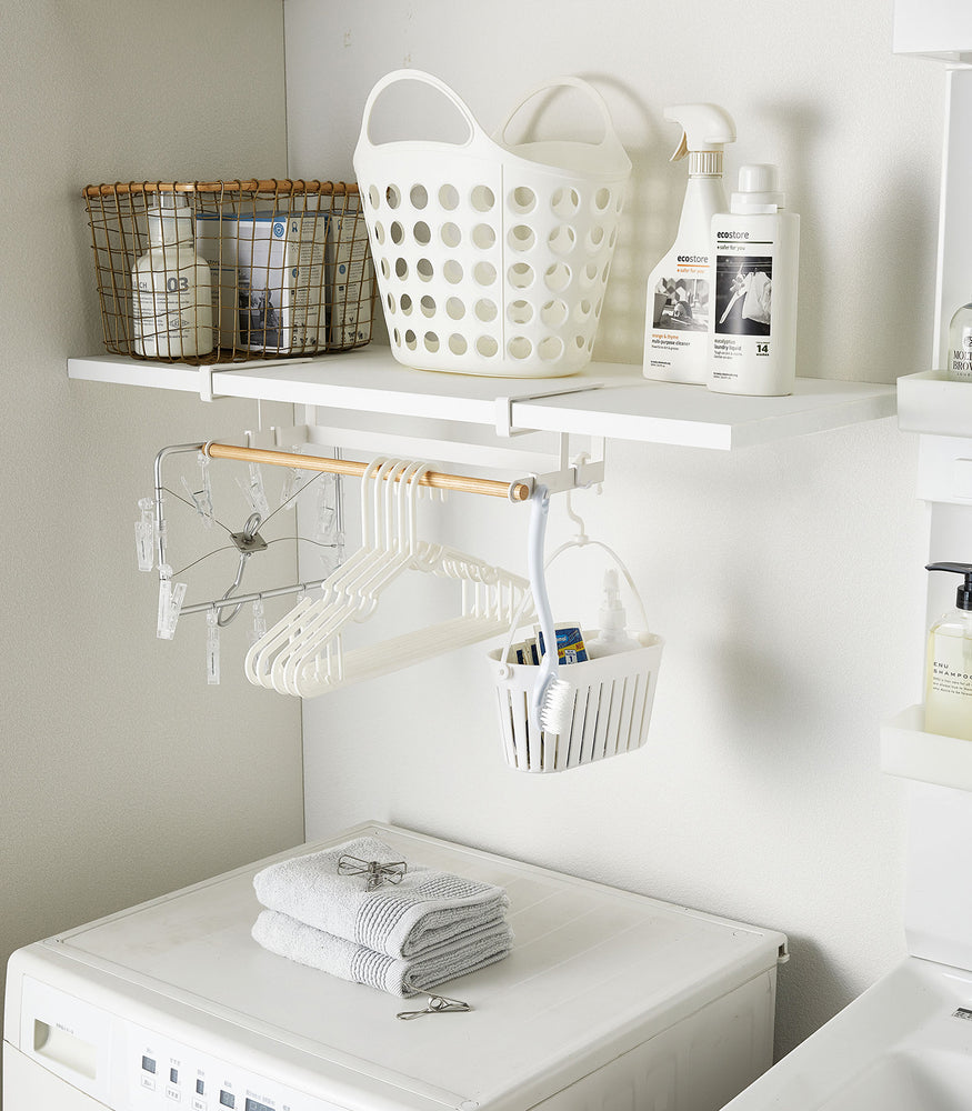 View 2 - White Undershelf Hanger in laundry room holding laundry accessories by Yamazaki Home.