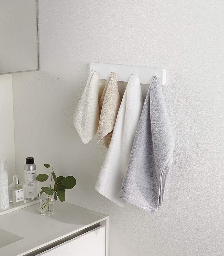 View 2 - White Push Dish Towel Holder holding towels in bathroom by Yamazaki Home.