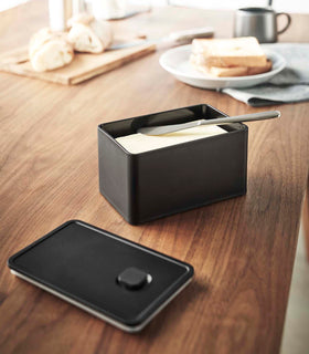 Front view of black Vacuum-Sealing Butter Dish holding butter on table by Yamazaki Home. view 8