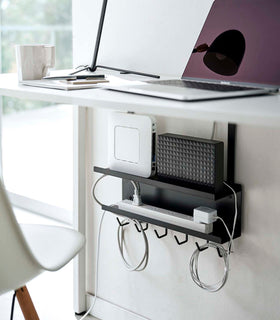 Black Wall-Mount Cable and Router Storage Rack holding routers and power cord under desk by Yamazaki Home. view 8
