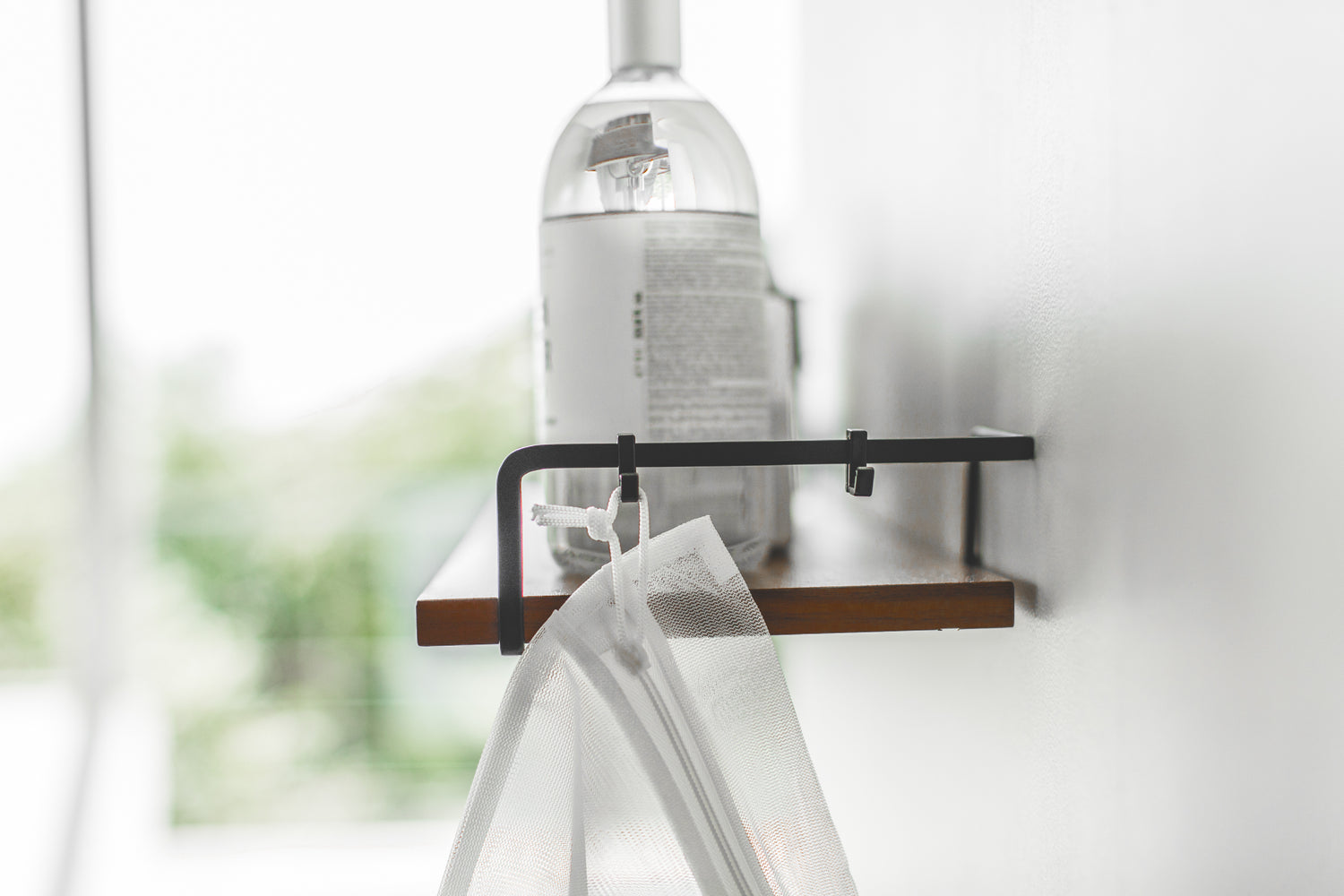 View 8 - Side view of Wall-Mounted Shelf holdling cleaning items and mesh bag by Yamazaki Home.