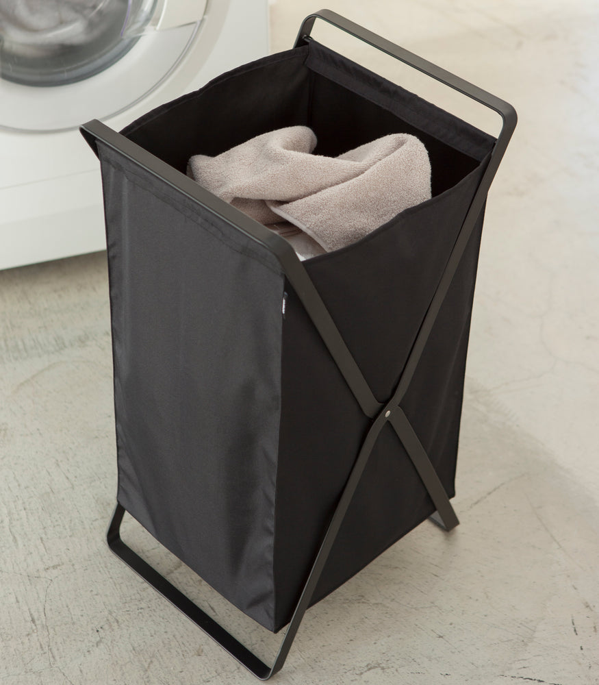 View 10 - Black Laundry Hamper Storage Organizer holding towel in laundry room by Yamazaki Home.