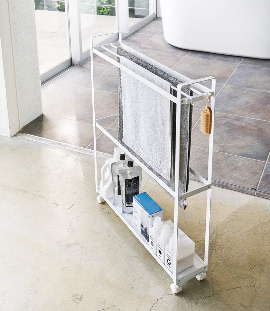 View 2 - White Rolling Towel Rack holding cleaning products and towels by Yamazaki Home.