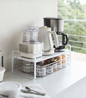 White Expandable Countertop Organizer expanded holding small appliances on kitchen countertop by Yamazaki Home. view 3