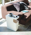 White Side Table Trash Can in living room holding coffee cup and phone by Yamazaki Home.