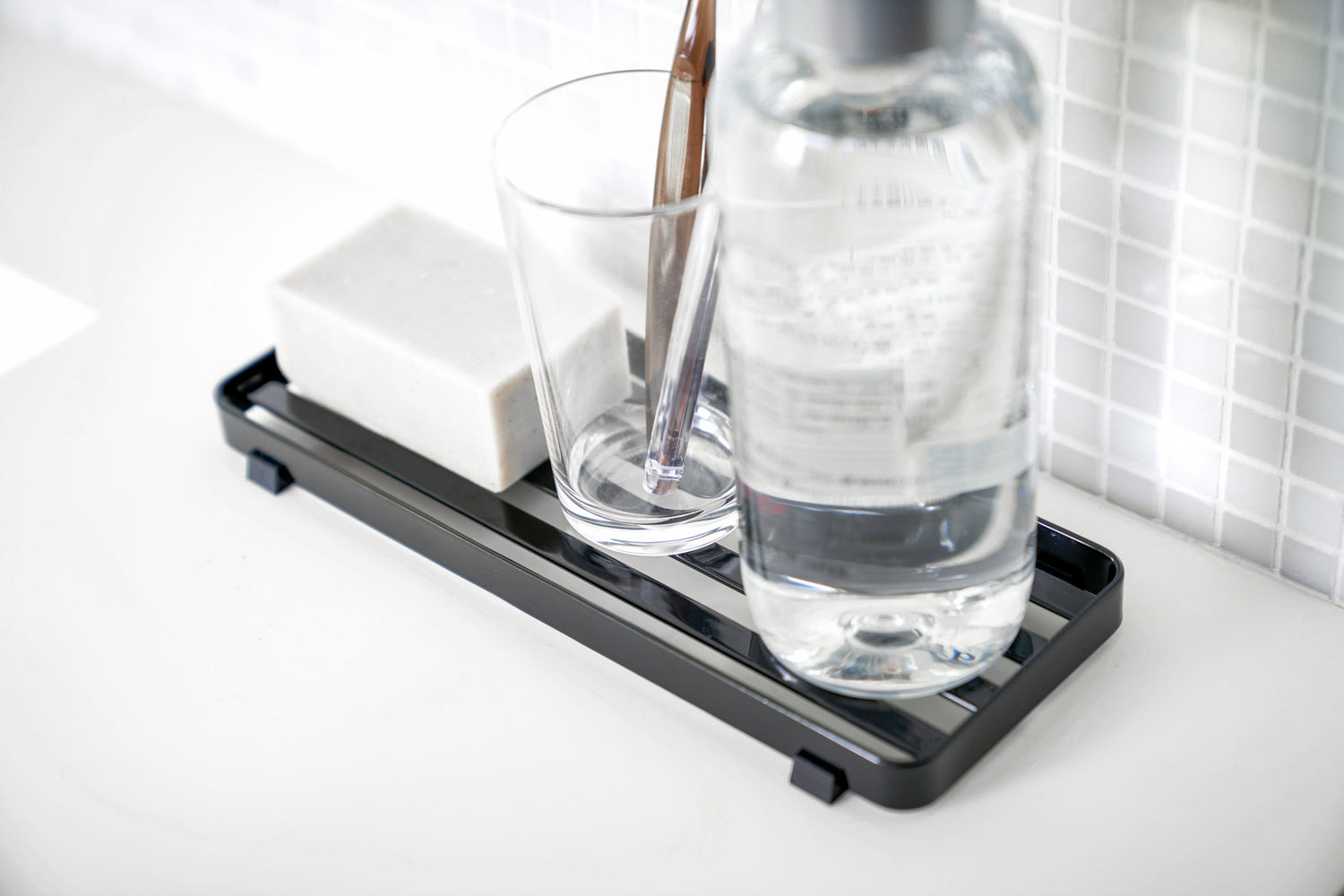 View 10 - Close up aerial view of black Slotted Tray holding soap, toothbrush, and bottle by Yamazaki Home.