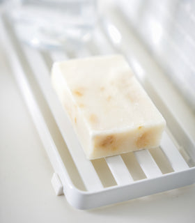 Close up side view of white Slotted Tray holding soap bar by Yamazaki Home. view 5