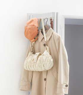 White Over-the-Door Hanger holding hat, bag, jacket, and belt on closet door  by Yamazaki Home. view 4