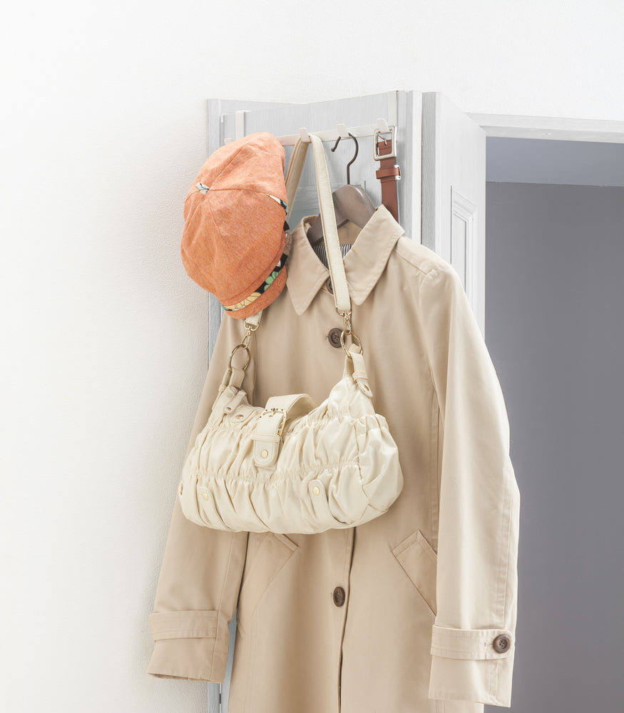 View 4 - White Over-the-Door Hanger holding hat, bag, jacket, and belt on closet door  by Yamazaki Home.