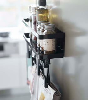 Side view of black Magnetic Organizer with Easy-Grip Rotating Clips holding spices and kitchen items by Yamazaki Home. view 10