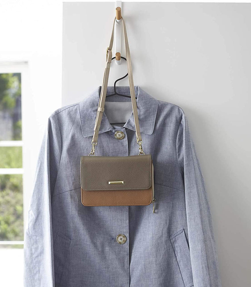View 6 - Front view of white Over-the-Door Hook holding shirt and purse by Yamazaki Home.