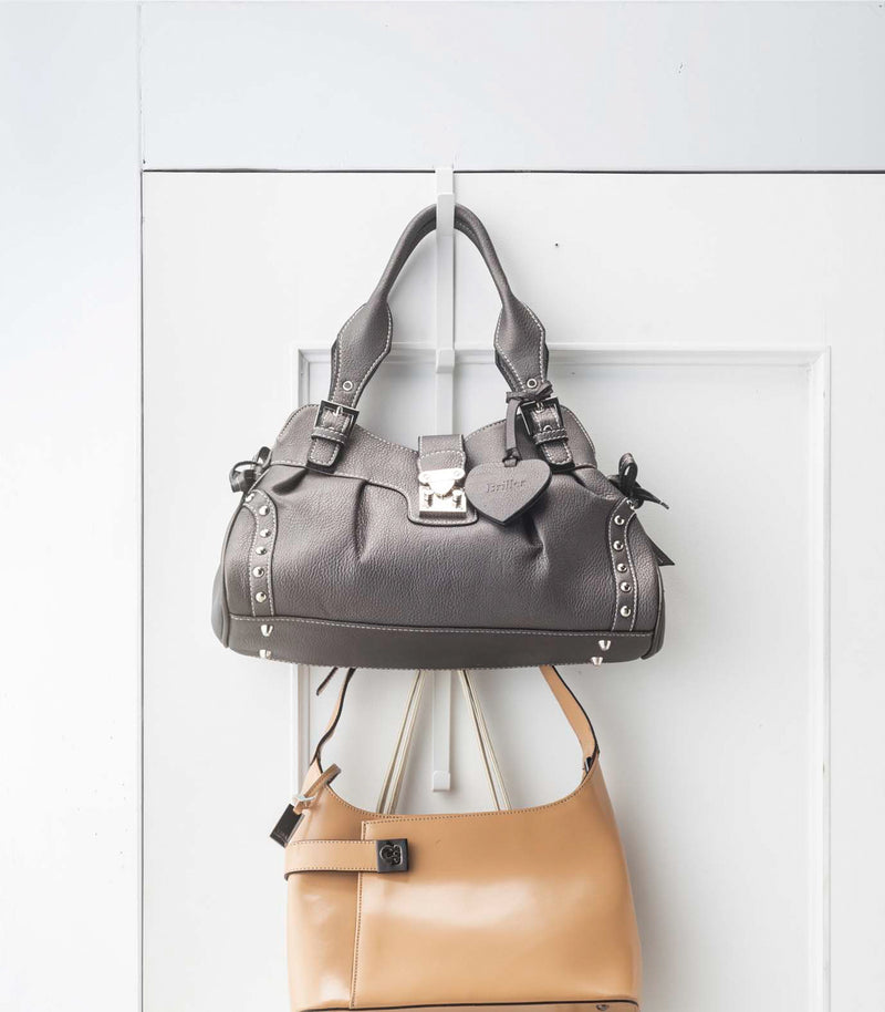 Front view of white Over-the-Door Hanger on door displaying purses by Yamazaki Home.