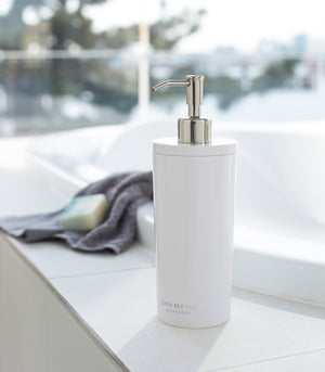 Front view of white Shampoo Dispenser on bathtub edge by Yamazaki Home.