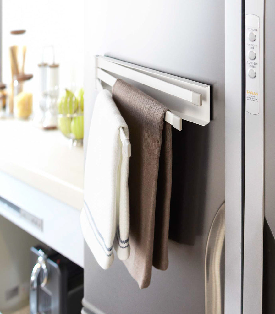 View 3 - Side view of white Magnetic Dish Towel Hanger holding towels in kitchen by Yamazaki Home.