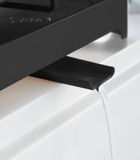 Close up of black Slim Dish Rack water spout draining into sink by Yamazaki Home. view 14
