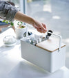 Person holding handle of white Makeup Organizer containing makeup products by Yamazaki Home.