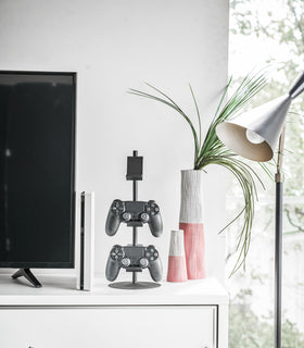 Front view of black Controller Stand displaying game controllers on TV stand by Yamazaki Home. view 8
